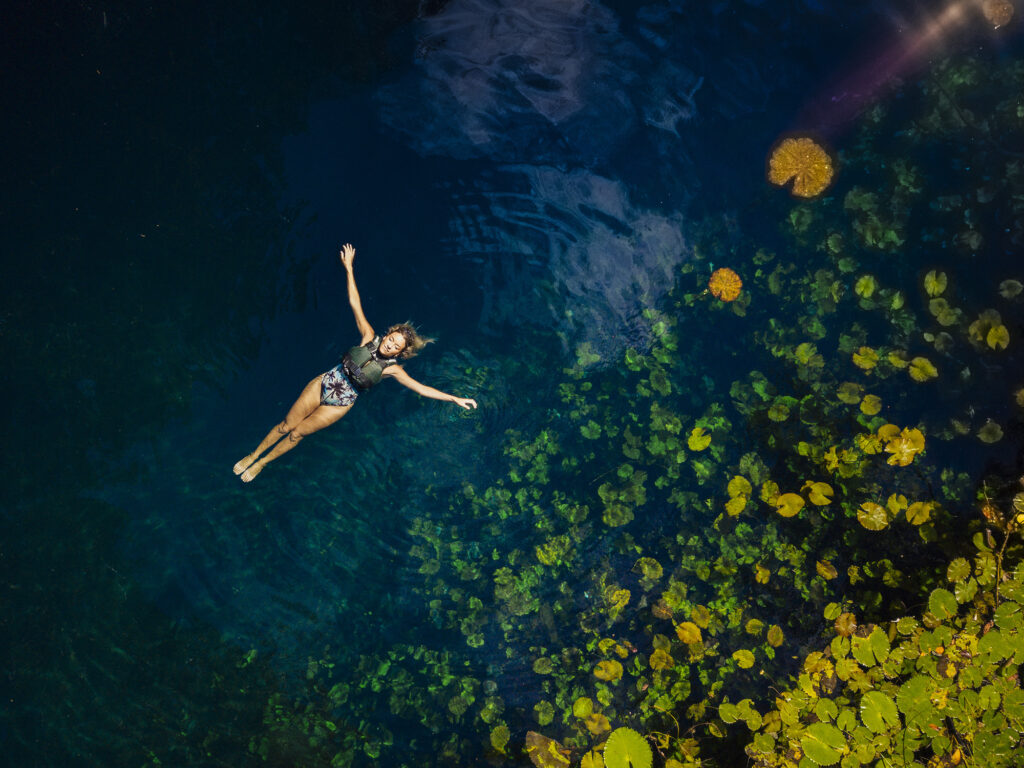 Lady swimming next to Lilly pads during the Xenotes Tour
