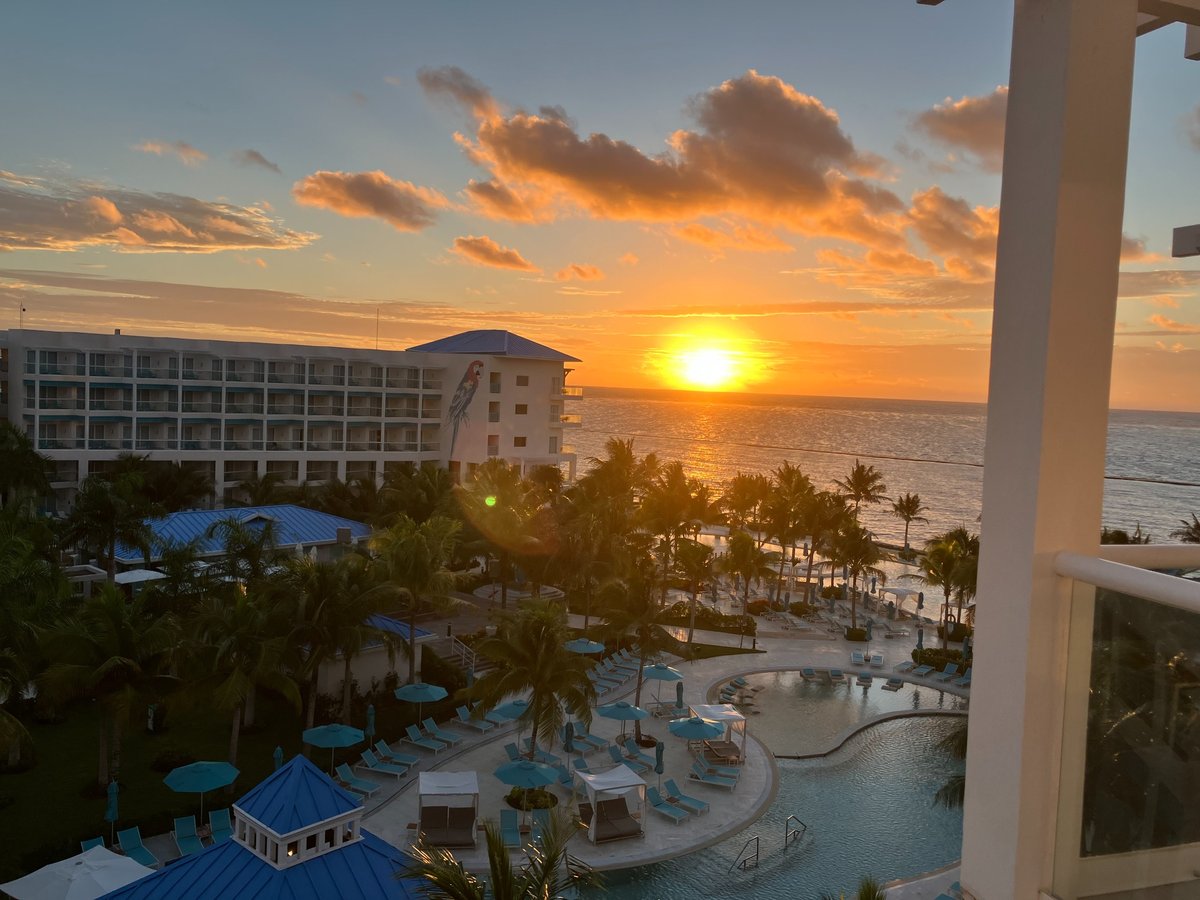 Ocean view from our balcony at Margaritaville Island Reserve Riviera Maya, with golden sunlight over the pools and palm trees